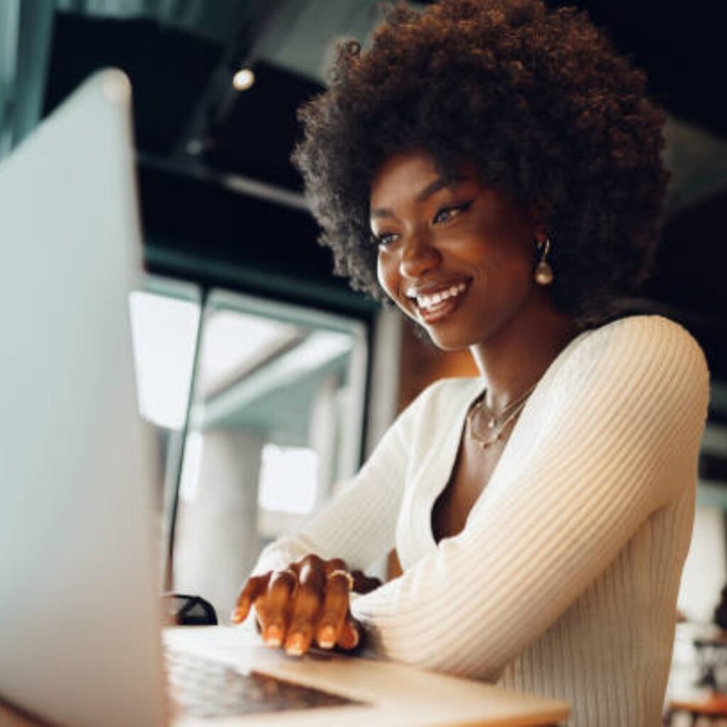 zvvt community membership promo image - smiling black woman with afro hair and a white top, scrolling on a laptop.